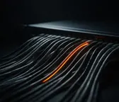 Cables negros en paralelo con una traza naranja iluminada, metáfora de un flujo automatizado